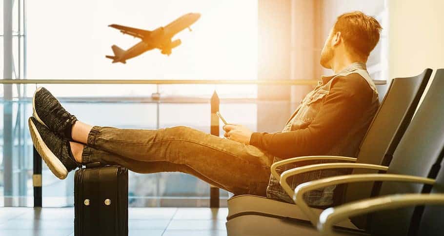 mann der am flughafen auf flug in die ferien wartet als symbol für fringe benefits als teil der lohnvorstellung bei der bewerbung 
